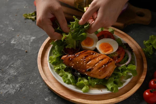 Kadın aşçı pişirmek ya da haşlanmış yumurta ve kızarmış teriyaki tavuk göğsü ile sağlıklı salata karışımı yapmak. yakın plan resim