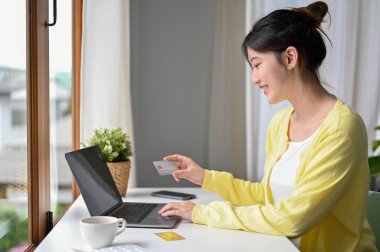 Arka manzara, kafede oturan güzel Asyalı kadın internet sitesinden alışveriş yapmayı ve kredi kartıyla ödeme yapmayı seviyor..