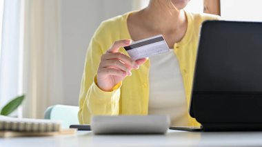 Milenyum kadını dijital tablet bilgisayar kullanıyor ve ofis masasında kredi kartı tutuyor. İnternetten alışveriş ve ödeme konsepti. yakın plan resim