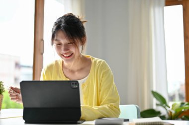 Milenyum kadını dijital tablet bilgisayar kullanıyor ve ofis masasında kredi kartı tutuyor. İnternetten alışveriş ve ödeme konsepti. yakın plan resim