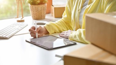 Masada oturan küçük KOBİ iş kadını dijital tablet kullanarak online pazarlama içeriğini yaratıyor. kırpılmış yakın plan resim