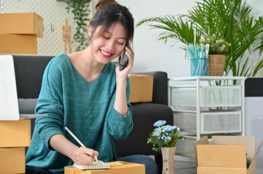 Çekici bir Asyalı genç bayan küçük işletme girişimcisi müşterilerinin siparişlerini almak için onun teslimat servisini arıyor. Çevrimiçi iş kavramı