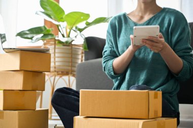 Cropped image, Female online seller using calculator to calculate the delivery fee for her packages.