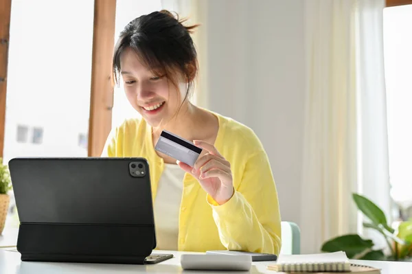 一位快乐的亚洲年轻女性正在平板电脑上浏览时尚购物网站 并用信用卡购物 网上购物概念 — 图库照片