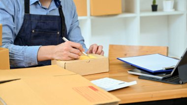 Erkek mağaza sahibi stok odasında teslimat için müşteri siparişi paketini topluyor. kırpılmış resim