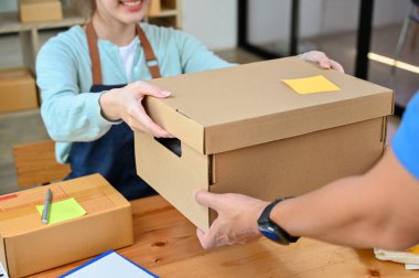 Kadın bir karton kutu ya da paket posta kutusunu teslimatçıya veriyor. Ürün nakliyesi, online alışveriş. kırpılmış resim