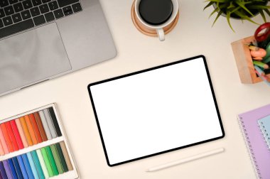 Modern creative graphic designer workspace or student workspace with tablet white screen mockup, crayons, laptop and accessories on white table. top view