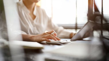 Professional businesswoman working at her office desk, using calculator, working on accounts report. cropped image