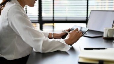Ofis masasında dijital tablet dokunmatik ped kullanan Asyalı çalışan bir kadın buluşma programını planlıyordu. dikey görünüm, kırpılmış resim