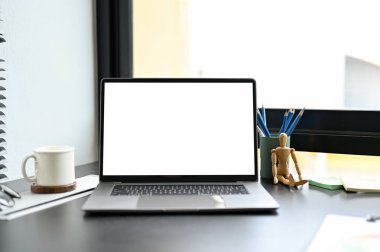 Taşınabilir dizüstü bilgisayar, beyaz ekran maketi ve ofis malzemeleri modern karanlık ofis masasında. yakın plan resim