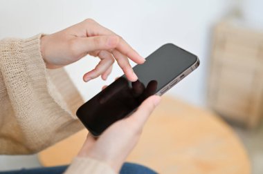 Yakın çekim, kadın rahat oturma odasında akıllı telefon kullanıyor. - Ne? Telefon siyah ekran modeli.