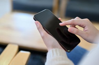 Close-up shot, A woman hand tapping or touching on smartphone screen. Female using cellphone, chatting with her friends, searching online informations.