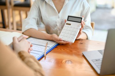 Dişi emlakçı hesap makinesi kullanıyor ve vergi bedelini müşterisine gösteriyor. yakın plan resim