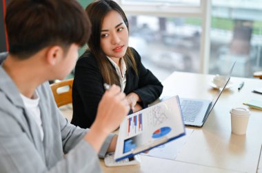 Milenyum Asyalı kadın ofis çalışanı. Ofiste erkek arkadaşıyla birlikte çalışıyor..