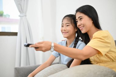 Anne haftasonunu kızıyla oturma odasında TV programı ya da komik çizgi film izleyerek geçiriyor. Mutlu aile zamanı konsepti.