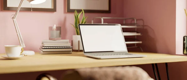 Modern pink feminine home workstation with notebook laptop mockup, supplies and accessories on wood table against pastel pink wall. close-up, 3d rendering, 3d illustration