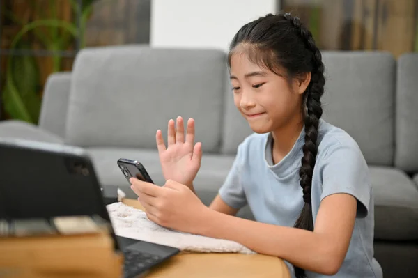 Happy Asian Kid Una Giovane Ragazza Siede Soggiorno Utilizzando Smartphone — Foto Stock