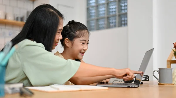 즐거운 아시아인 엄마는 노트북 화면을 보면서 집에서 온라인 숙제를 하도록 — 스톡 사진