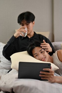 Yakışıklı Asyalı genç eşcinsel çift yatak odasında rahatlıyor, tabletle film izliyorlar. Erkek arkadaşının kucağında yastığa uzanmış bir adam. Romantik genç eşcinsel çift.