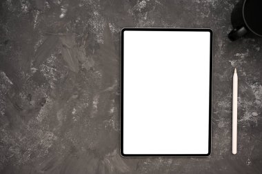 Modern çalışma alanı dijital tablet beyaz ekran modeli, stilus kalem ve gri grunge desenli arka planda kopyalama alanı. en üstteki görünüm