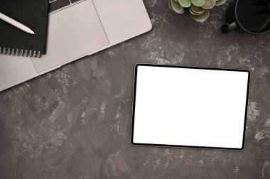 Hippi çalışma alanı üst görünümü, dijital tablet boş ekran modeli, dizüstü bilgisayar ve kırsal gri masa arkaplanı aksesuarları ile.