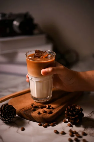特写图片 一只手拿着或者端着一杯冰镇的拿铁放在木板上的男性手 咖啡饮料 — 图库照片