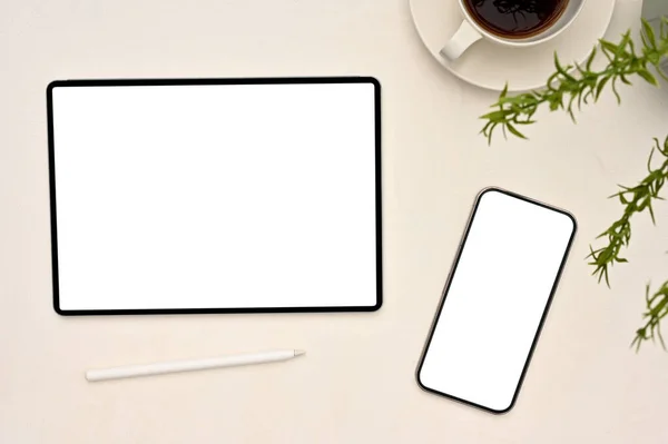 オーバーヘッドショット デジタルタブレットやスマートフォンの白い画面のモックアップ スタイラスペン 白いテーブルの背景にコーヒーや装飾工場のカップ — ストック写真