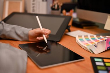 Kadın grafik tasarımcısı veya iç mimar, dijital tablet kullanarak ofis masasında oturuyor ve proje ödevi üzerinde çalışıyor. kırpılmış
