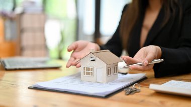 Evrakları ve kadın emlakçıları olan güzel bir ev modeli. Ev sigortası, ev mülkü yatırım konsepti.