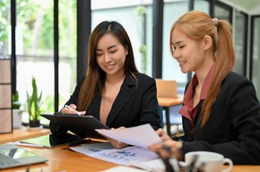 İki güzel Asyalı kadın finans danışmanı finansal planı tartışıyor, çalışıyor, birlikte planlıyorlar..