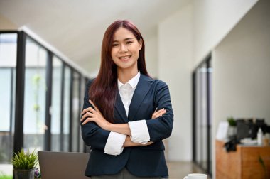 Çekici, kendine güvenen, resmi giyinmiş Asyalı bir iş kadınının portresi ofis odasında katlanmış duruyor..