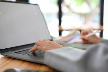 Kesilmiş görüntü, odaklanmış el, ofis masasındaki klavye dizüstü bilgisayarında yazı yazan bir iş kadını elleri..