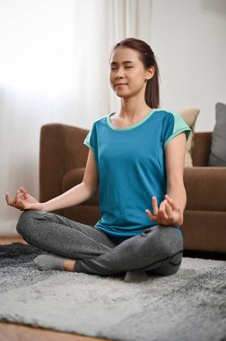 Güzel bir Asyalı kadının portresi halıya oturmuş yoga nilüfer pozu çalışıyor. Evde meditasyon.