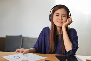 Çekici Asyalı kadın, modern kablosuz kulaklıklarıyla evde müzik dinlemeyi seviyor..