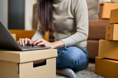 Dişi bir serbest çalışan, küçük bir işyeri sahibi müşteri sorusunu depo odasındaki dizüstü bilgisayarla cevaplıyor. KOBİ, E-ticaret konsepti. kırpılmış resim