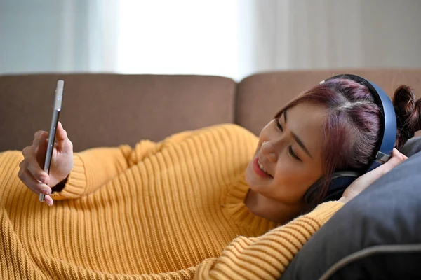 Приваблива Молода Азіатка Відпочиває Вдома Лежачи Зручному Дивані Використовуючи Смартфон — стокове фото