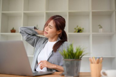 Ofis masasında çalışan yorgun Asyalı iş kadını uzun süre çalıştıktan sonra sırtı ve omuzları ağrıyormuş. Ofis sendromu kavramı