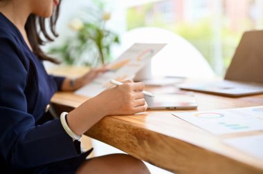 Çekici Asyalı iş kadını ya da modern parlak ofis masasında çalışan kadın bir finans raporu okuyor. kırpılmış resim