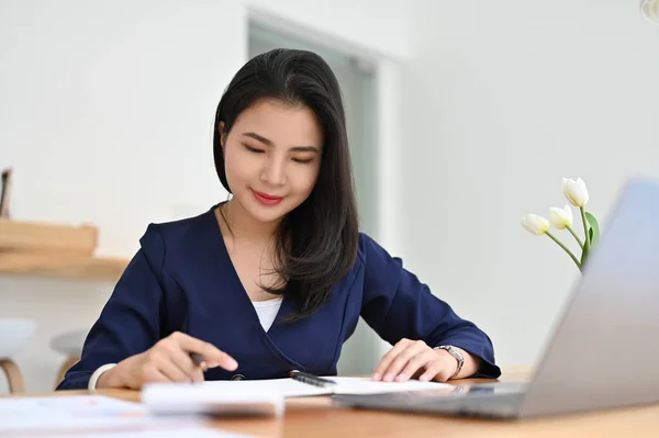 迷人的年轻亚洲女商人或会计坐在她的写字台前 分析报告中的商业会计销售情况 — 图库照片