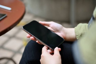 Bir kadının elinde akıllı telefon siyah ekran modeli. Yakın plan görüntü, parkta oturan ve akıllı telefon kullanan bir kadın..