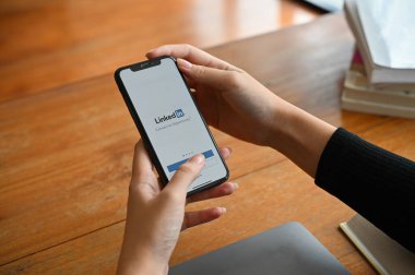 Chiangmai, Tayland - 29 Haziran 2022: Bir iş kadını veya kadın eli ekranda Linkedin 'in web sitesi olan bir akıllı telefonu tutuyor. Linkedin iş ve iş bulma sitesi.