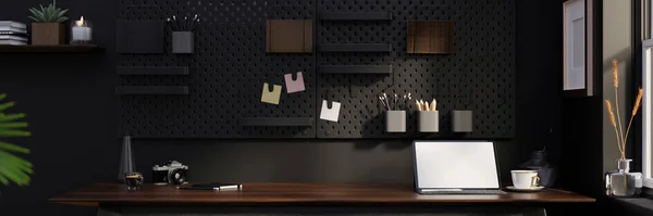 Stylish black home workspace interior design with portable tablet touchpad white screen mockup, accessories and copy space on wood table, black pegboard on black wall. 3d rendering, 3d illustration