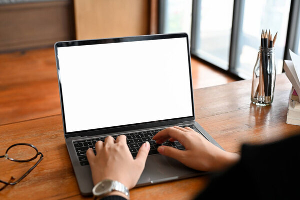 A businessman working at his desk, using laptop computer to manage his task. Laptop white screen mockup.