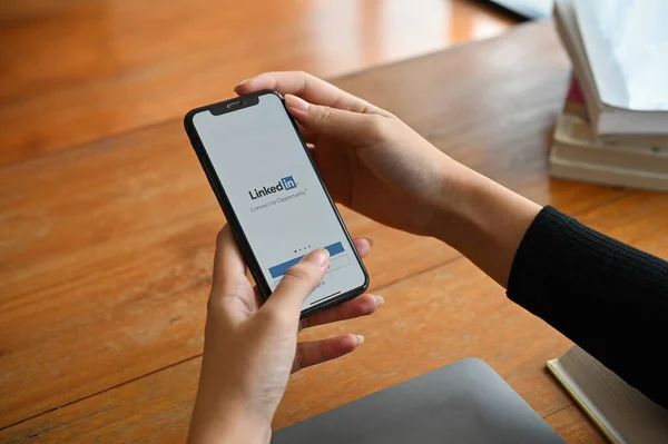 Chiangmai, Tayland - 29 Haziran 2022: Bir iş kadını veya kadın eli ekranda Linkedin 'in web sitesi olan bir akıllı telefonu tutuyor. Linkedin iş ve iş bulma sitesi.