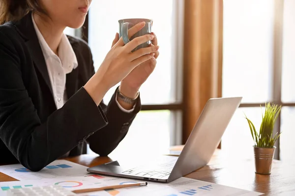 作物のイメージ コーヒーカップを保持ビジネスマンの女性 彼女のオフィスの机で彼女の一日を開始する朝のコーヒーを飲みます — ストック写真