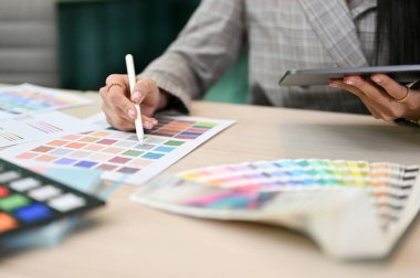Kırpılmış resim, ofis masasında çalışan kadın grafik tasarımcısı, renk örneklerini kontrol ediyor..