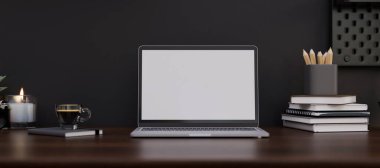 Modern koyu renkli çalışma alanı dizüstü bilgisayarı beyaz ekran maketi, kırtasiye malzemesi, kitap ve siyah duvarın üzerindeki koyu ahşap masada bir fincan kahve. 3d görüntüleme, 3d illüstrasyon