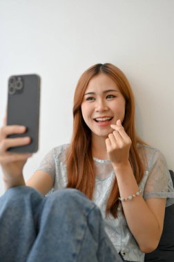 Çekici güzel Asyalı kadın online sosyal medyasında canlı yayında erkek arkadaşıyla görüntülü görüşme yapıyor ya da akıllı telefonuyla selfie çekiyor..
