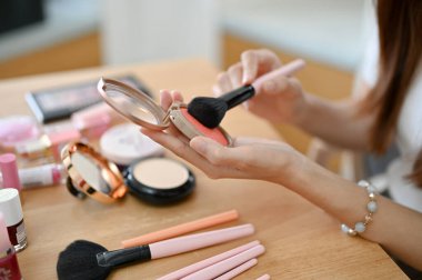 Güzel bir milenyum dişisi makyajını yapıyor, yeni bir allık sürüyor. kırpılmış ve kapatılmış resim