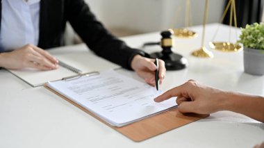 Kesilmiş ve odaklanmış bir şekilde profesyonel bir kadın iş avukatı müşterisiyle bir sözleşme imzalamak için ofisinde toplantı yapıyor..